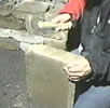 Using the hammer to hammer down the side of the capping stone