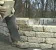 Laying the last layer of retaining wall blocks.